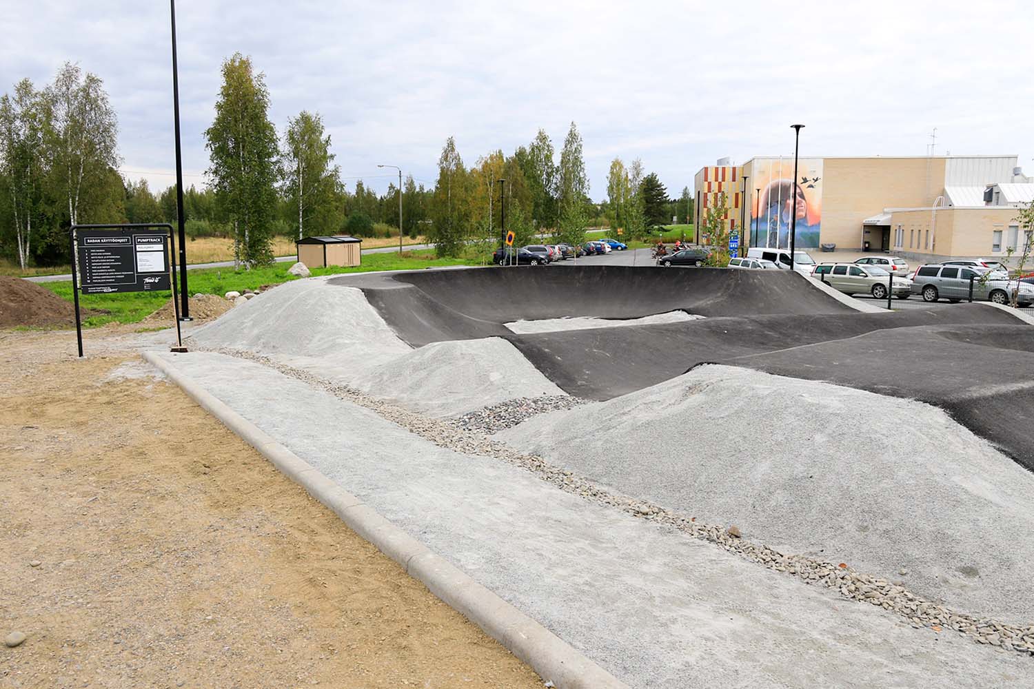 Kuvassa Polvijräven kunnan pumptrack-rata, taustalla parkkipaikka ja vapaa-aikatalo Vapari.