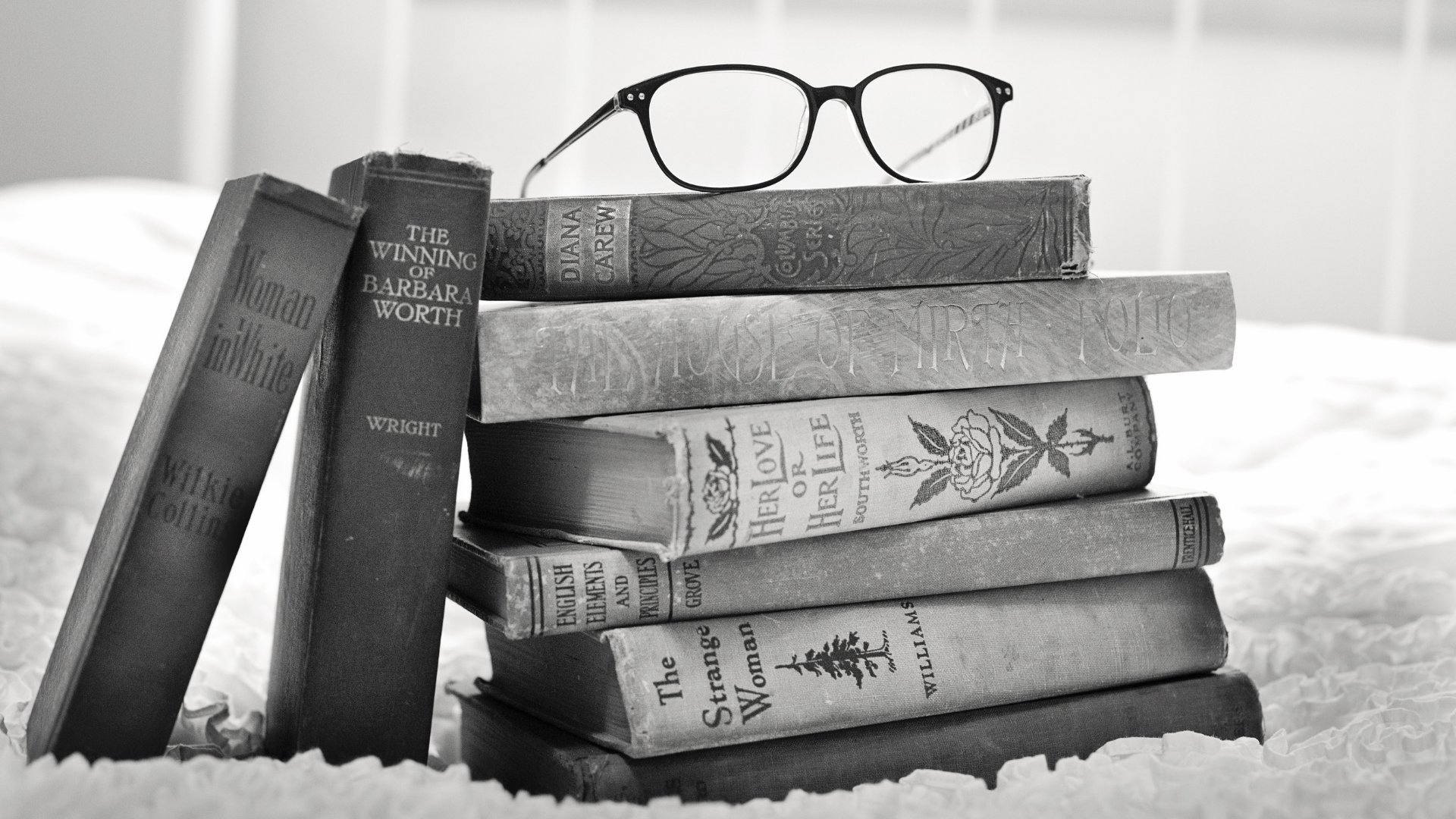 Vanhoja kirjoja pinossa, kirjapinon päällä on silmälasit